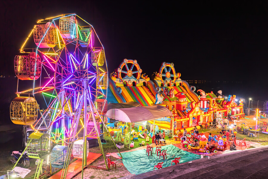 Illuminated_Ferris_wheel,_bouncing_castle_and_carousel_at_night_in_a_funfair_in_Vientiane,_Laos (1).jpg